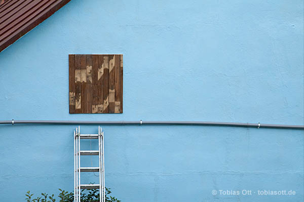 Fassade mit Leiter und Holztür in Hellblau